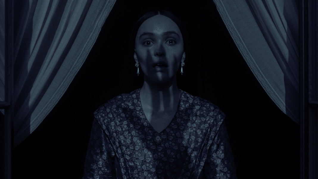 Lily-Rose Depp looking terrified as Count Orlok&#039;s shadowy hand spreads across her in 2024&#039;s Nosferatu.